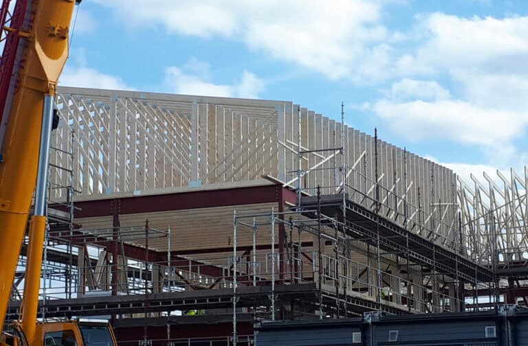 Byggeprosjekt i fremgang med trebeskytning og stillas på nybygget slik at det blir tryggere og mer effektivt.
