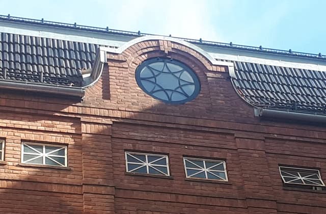 Eksponert tak og vindusdesign på en renovert bygning, som viser arkitektoniske detaljer og moderne byggkonsulenttjenester.